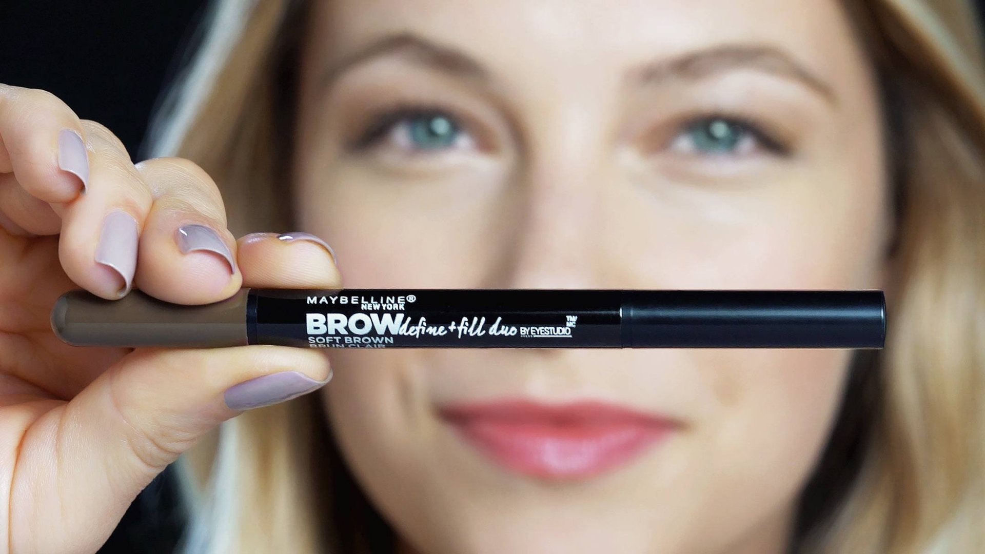 Фокус на засіб Maybelline New York Brow Define and Fill Duo, який тримає жінка з білявим волоссям 